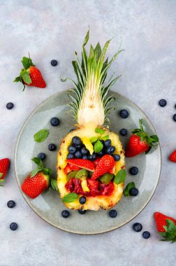 Delicious fruit salad of strawberries, kiwi, berries and orange in half a pineapple. Tropical fruit