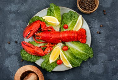 Cooked lobster with greens and lemon on a plate. Seafood. Top view.