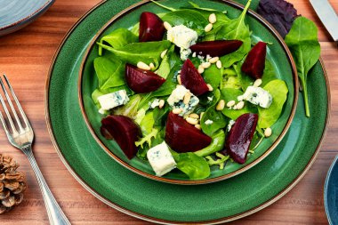 Beetroot salad with beets, blue cheese, herbs and pine nuts on the green plate
