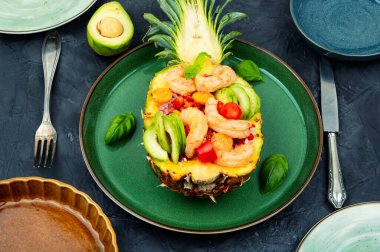Salad in pineapple with rice, vegetables and shrimps on the table