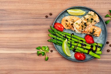 Tahta bir masada sağlıklı alabalık, kuşkonmaz ve domates..