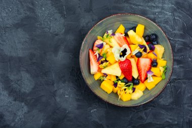 Ananas salatası, çilek ve böğürtlen, yenilebilir çiçeklerle süslenmiş. Vejetaryen yemeği. Boşluğu kopyala.