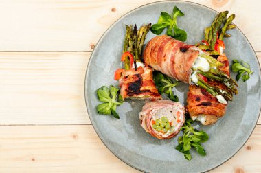 Ahşap masaya kuşkonmaz ve krem peynirle doldurulmuş pastırmalı rulo köfte. Üst Manzara. Metin için boşluk.
