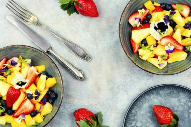 Yenilebilir çiçeklerle süslenmiş ananas ve böğürtlen salatası. Düşük karbonhidrat diyeti