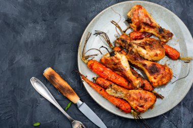 Tabakta havuçla pişirilmiş lezzetli tavuk bacakları. Metin için boşluk.