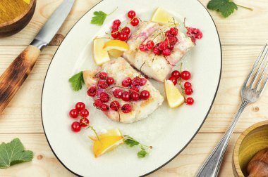 Ahşap masada kırmızı üzümlü kızarmış balık filetosu. Morina balığı.