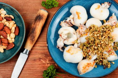 Ahşap masada fındık salatasıyla servis edilen taze mürekkep balıkları..