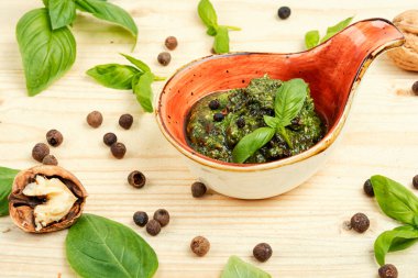 Beyaz ahşap bir masada taze fesleğenden mis kokulu pesto sosu hazırlamak..