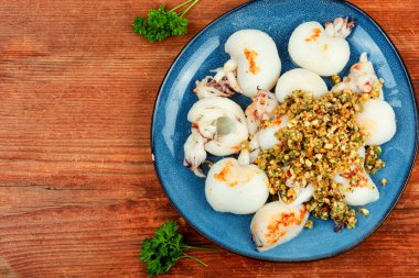 Ahşap masada fındık salatasıyla servis edilen taze mürekkep balıkları..