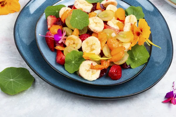 Vitamin salad with banana, strawberries, grapes and nasturtium. Low calorie desserts.