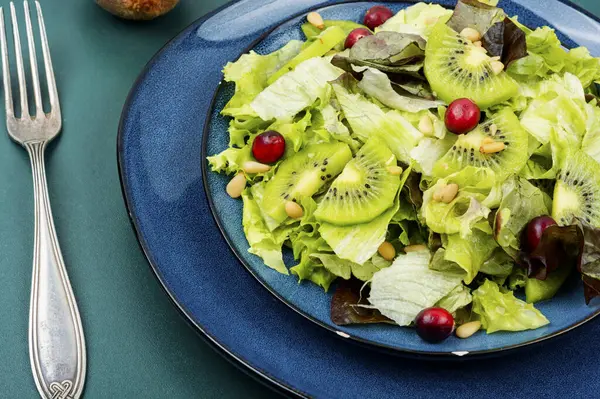 Fresh summer salad of kiwi, greens, berries and pine nuts. Bowl with salad.