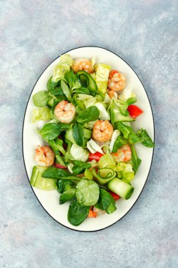 Sebzeli taze salata ve deniz ürünleri, beyaz tabakta karides. Sağlıklı beslenme.