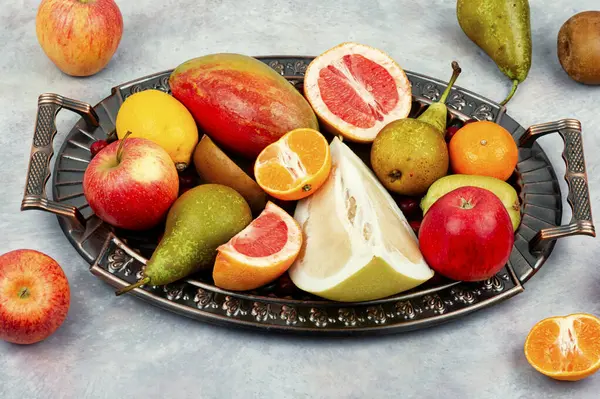 Apples, pears, mangoes and citrus fruits on a stylish tray.