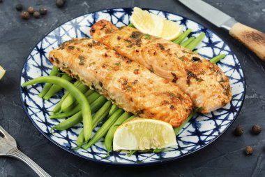 Çalı yeşil fasulyelerle süslenmiş lezzetli somon biftekleri. Pişmiş balık porsiyonu..