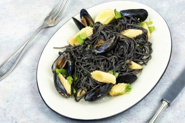 Beyaz tabakta midyeli siyah deniz ürünleri makarnası. Deniz mahsullü spagetti.