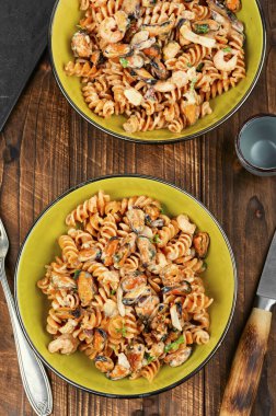 Ev yapımı deniz mahsullü makarna, midyeli makarna ve sade ahşap masada karides. Düz yatıyordu.