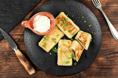 Ahşap yüzeyde et ve ekşi kremayla doldurulmuş ev yapımı krepler. Kahvaltıda krep..