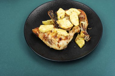 Ananasla servis edilen kızarmış tavuk budu. Siyah tabakta kızarmış tavuk eti..