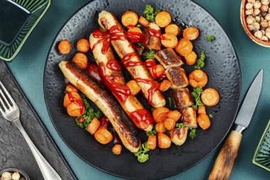 Tabakta kızarmış havuçla ızgara ızgara hindi Alman sosisi. Lezzetli yemek..