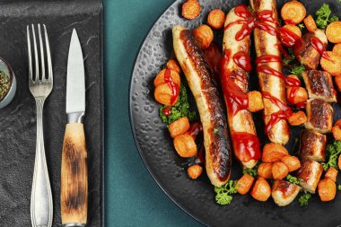 Ketçaplı ızgara hindi sosisi, tabakta kızarmış havuç. Barbekü menüsü. Üst görünüm.