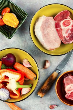 Pişmemiş çiğ et ve mutfak masasında farklı sebzeler. Çorba için malzeme seti. Üst manzara, düz uzanma.