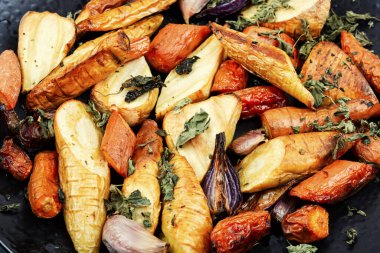 Fırında pişirilmiş havuç kökü, kırmızı soğan, havuç ve sarımsak. Kızarmış kök sebze. Kapat..