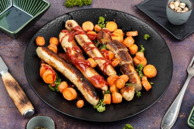 Fırında ya da ızgara hindi sosisi ve tavada kızarmış havuç. Almanca barbekü menüsü.