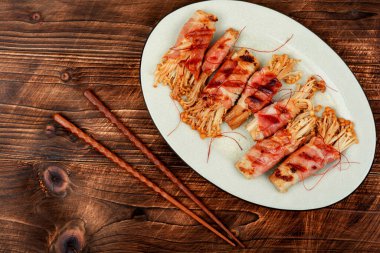 Enoki mantarıyla doldurulmuş domuz pastırması. Pastırmalı mantar. Kopyalama alanı olan düz.