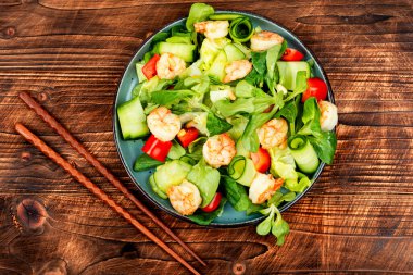 Taze sebze, ot, karides ve karides salatası. Tahta masada karides salatası.