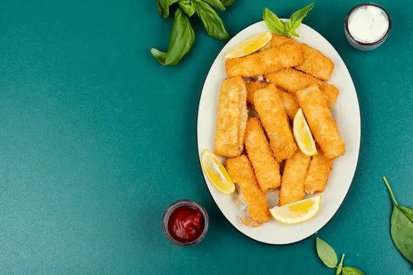 Crumbed fried fish fingers in sticks with sauce. Restaurant menu, cookbook recipe. Copy space.