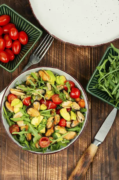 Ev yapımı lezzetli midye salatası, roka, domates ve ahşap masa üzerinde avokado. Düz yatıyordu.
