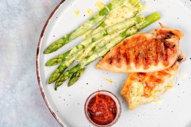 Barbekü ya da ızgara tavuk göğsü ve beyaz tabakta yeşil kuşkonmaz. Boşluğu kopyala.