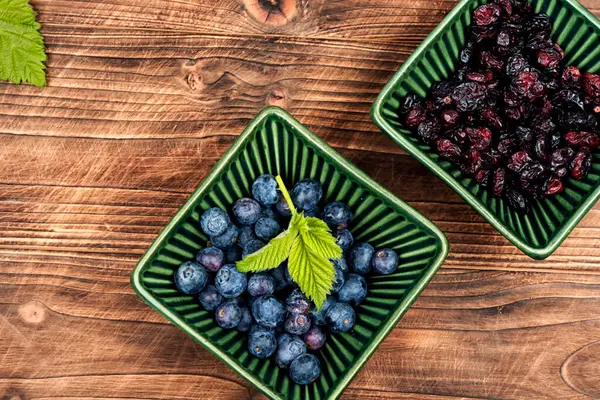 新鮮なブルーベリーと素朴な木製テーブルの乾燥クランベリーのヒープ レシピの場所 ロイヤリティフリーのストック写真