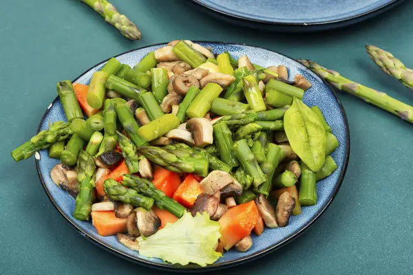 天然的绿色芦笋沙拉和烤蘑菇放在盘子里 蔬菜沙拉 图库图片