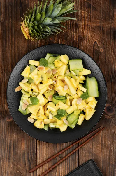 Eski ahşap masada taze ananas ve salatalık ile salata tabağı. Sağlıklı, dengeli, diyet yemekleri..
