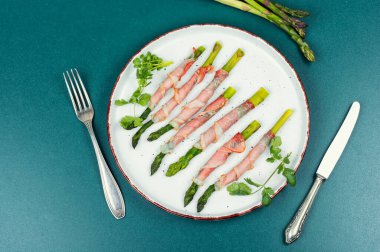 Pastırmada pişmiş taze yeşil kuşkonmaz. Üst görünüm.