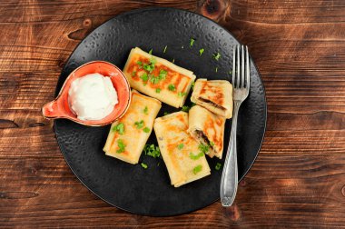 Sığır ciğeri ve ekşi kremayla doldurulmuş krepler. Kahvaltı için kırsal ahşap masada krep..