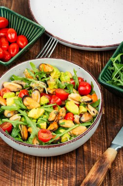 Midye salatası, roka, domates ve ahşap masa üzerinde avokado..