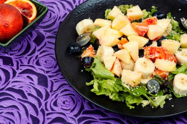 Taze kırmızı portakallı sulu salata, elma, muz ve marul. Sağlıklı beslenme.