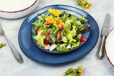 Yeşillik salatası, turp ve karahindiba çiçekleri bir tabakta.