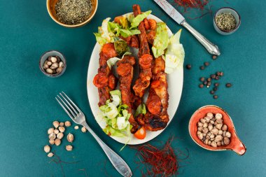 Koyu bir tabakta servis edilen domates soslu domuz pirzolası. Barbekü..