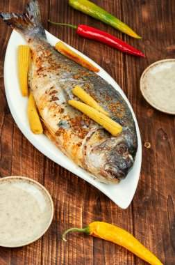 Köy ahşap masada küçük mısırla pişirilmiş Dorado balığı. Diyet ve temiz yemek. Koyu tahta arkaplan.
