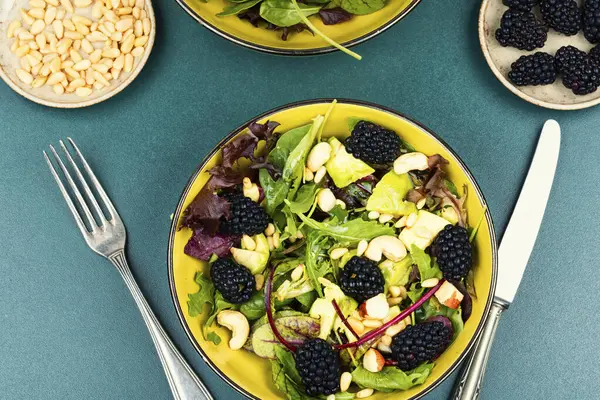 stock image Summer food, salad with fresh blackberries garnished with fresh herbs in plate on table. Flat lay.