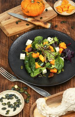 Yeşil salata, kabak, peynir ve kırsal ahşap masada yeşillikler. Sağlıklı ev yemekleri. Kırsal biçim