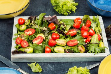 Çilekli domatesli parlak sulu salata ve modern taş tepside taze marul yaprakları. Sağlıklı yemek..