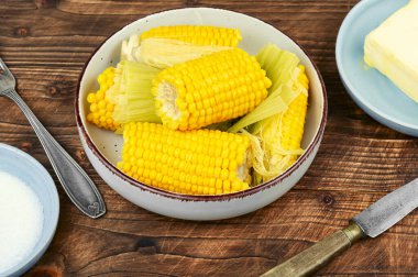 Kırsal ahşap masada tereyağı ve tuzlu ev yapımı altın mısır koçanı. Kırsal biçim.