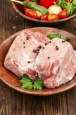 İki parça çiğ et ve pişirmek için taze sebze tabağı..