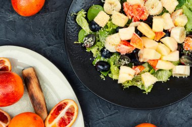 Kırmızı portakallı meyve salatası, elma, muz ve marul. Sağlıklı beslenme.