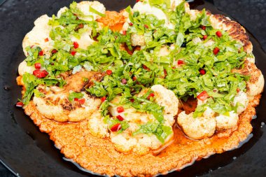 Bir tabak kavrulmuş karnabahar ve taze maydanoz ve sos. Kapat..