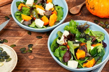 Yeşil salata, Hokkaido kabağı, peynir ve yeşillik. Ahşap arka planda ev yapımı sağlıklı yemekler..